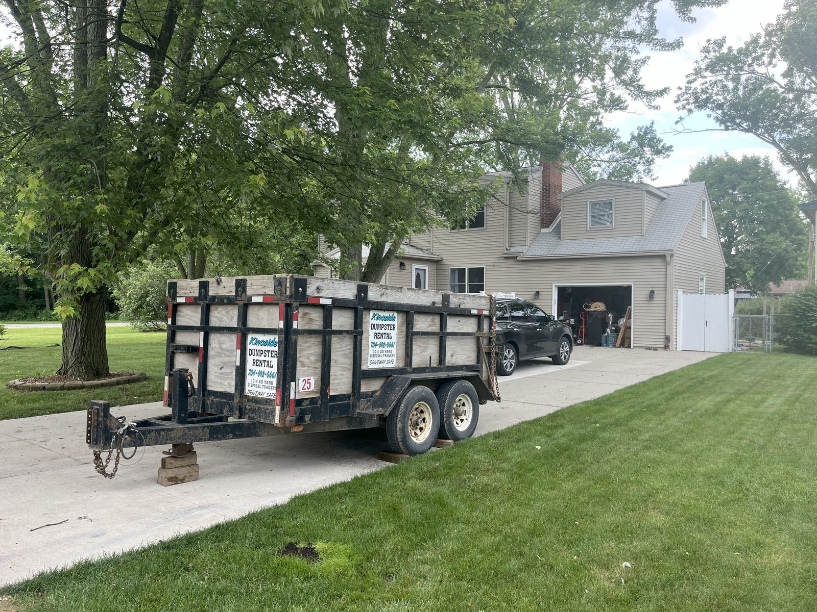 Kincaide branded rubber wheel dumpster trailer parked on a residential concrete driveway